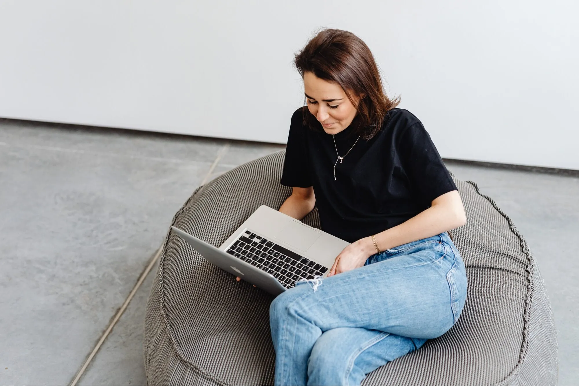 Woman sitting on bean bag chair looking at laptop
